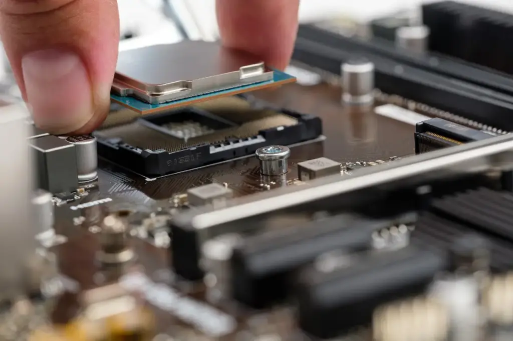 Hand setzt vorsichtig einen Prozessor in einen freien Sockel auf einem Mainboard – Detailaufnahme von Computerhardware